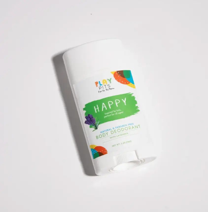 A Play Pits Happy lavender body deodorant stick lying on a white surface