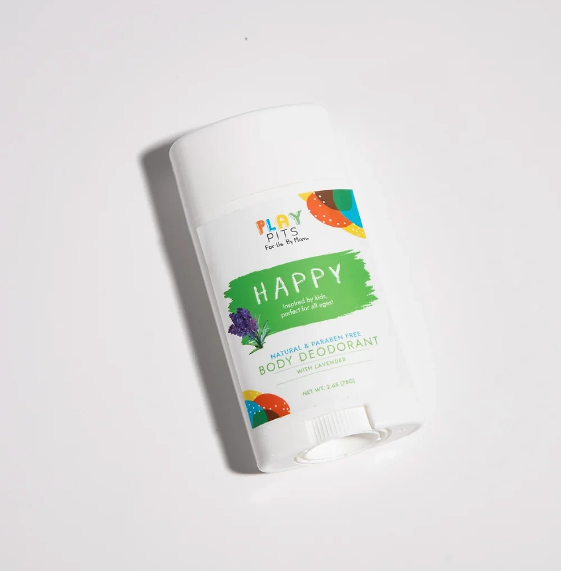 A Play Pits Happy lavender body deodorant stick lying on a white surface